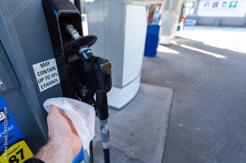 A mans hand with a disinfecting wipe in it holding a gas pump as a precaution during the Coronavirus pandemic 2020. photo