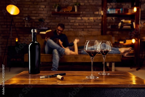 Glasses of red wine on table at home with couple