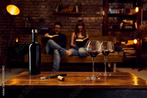 Glasses of red wine on table at home with couple