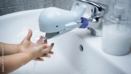 Baby toddler is washing hands rubbing with soap for corona virus prevention, hygiene to stop spreading coronavirus. Concept of early healthy hygiene learning and disease spreading prevention.