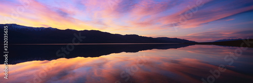 Panoramic view at sunset of flooded salt flats and Panamint Range Mountains in Death Valley National Park, California