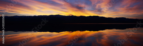 Panoramic view at sunset of flooded salt flats and Panamint Range Mountains in Death Valley National Park, California