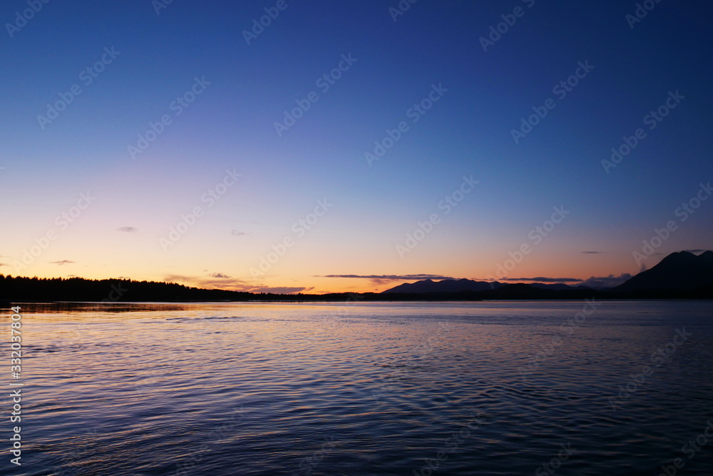 Sunset over distant mountains and calm water