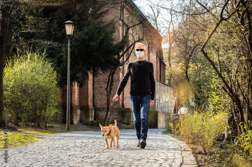 dog with  leash and owner with face mask walking outside