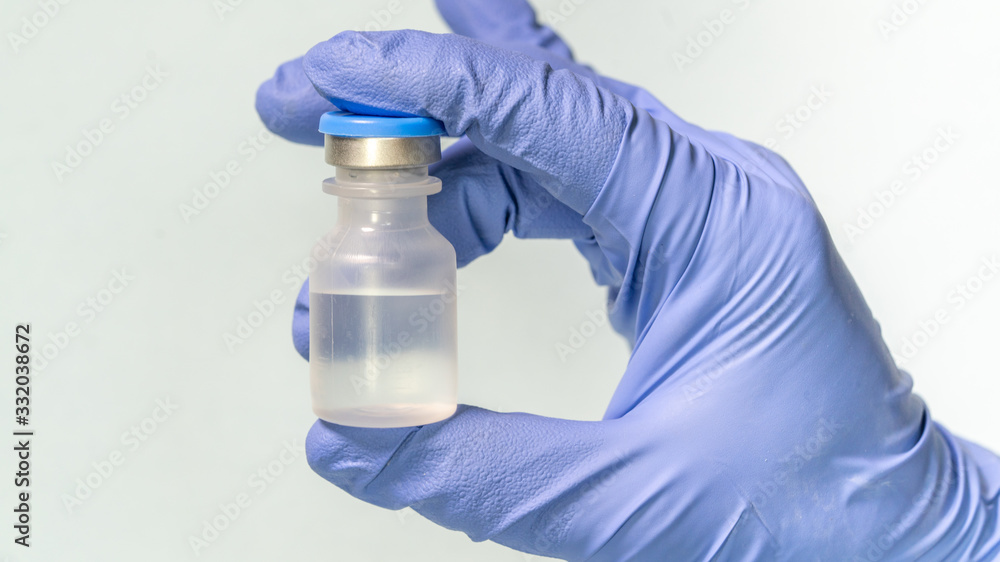 Close up of the hand of pharmacist female, wearing a latex glove, holding a medicine bottle. Pharmacist holding a vial at a drugstore, on Isolated background. Close up of the hand of pharmacist female, wearing a latex glove, holding a medicine bottle. Pharmacist holding a vial at a drugstore, on Isolated background.