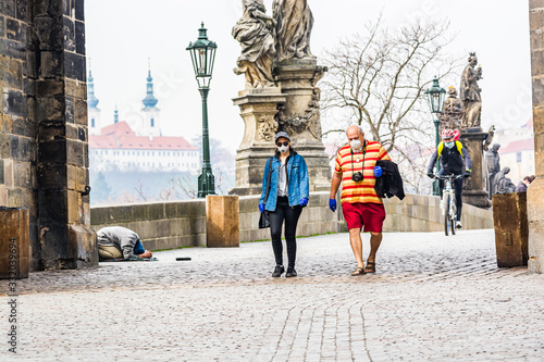 Prague, Czech republic - March 19, 2020. Tourists with surgical mask walking of Charles Bridge without tourist during Covid-19 travel ban