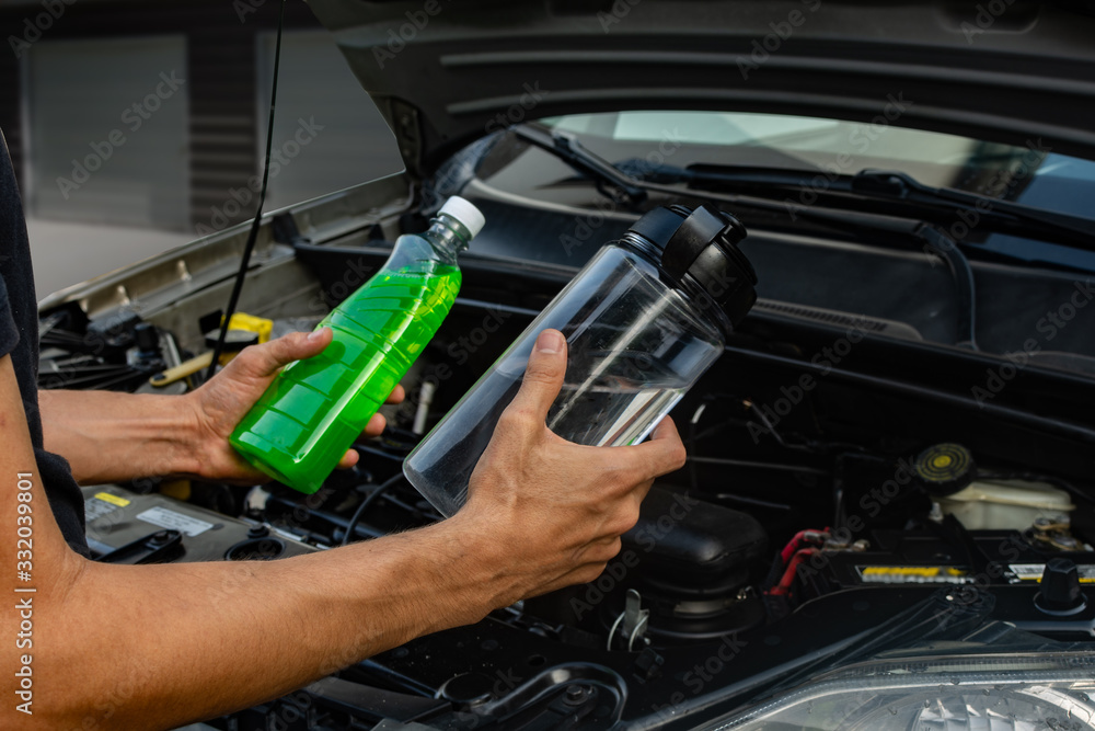 Topic of car repair shop: hands showing choice of coolant or water for car coolant system. maintenance fluids or engine products Topic of car repair shop: hands showing choice of coolant or water for car coolant system. maintenance fluids or engine products