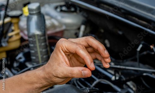 Car repair shop topic: Hand showing oil viscosity for car engine. lubrication and maintenance concept.