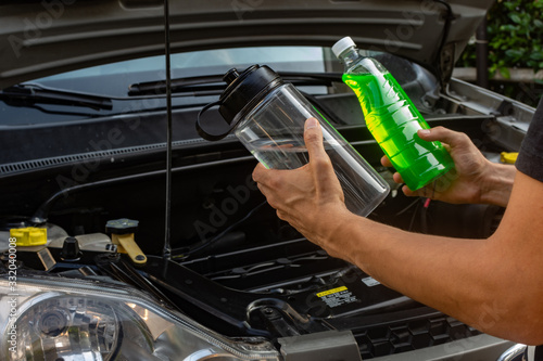  Topic of car repair shop: hands  showing choice of coolant or water for car coolant system. maintenance fluids or engine products photo
