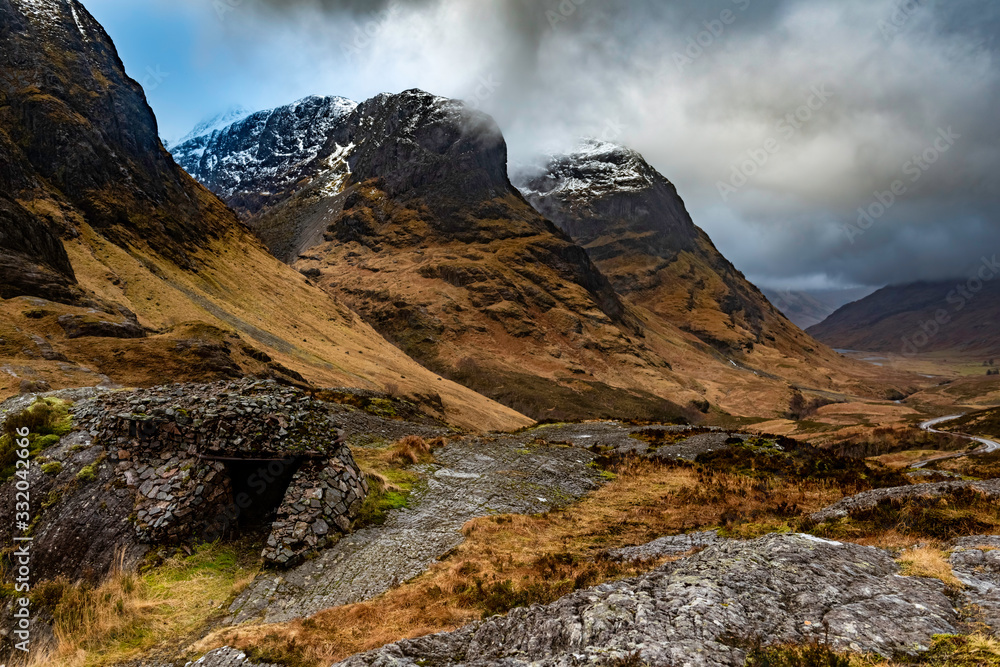Obraz premium Glencoe, Scotland - Jan 2020: Bothy shelter at the base of the 3 sisters as a winter storm passes overhead