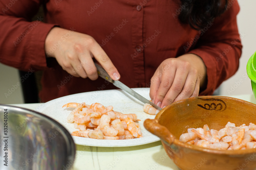 Unrecognizable woman cutting shrimps to cook them