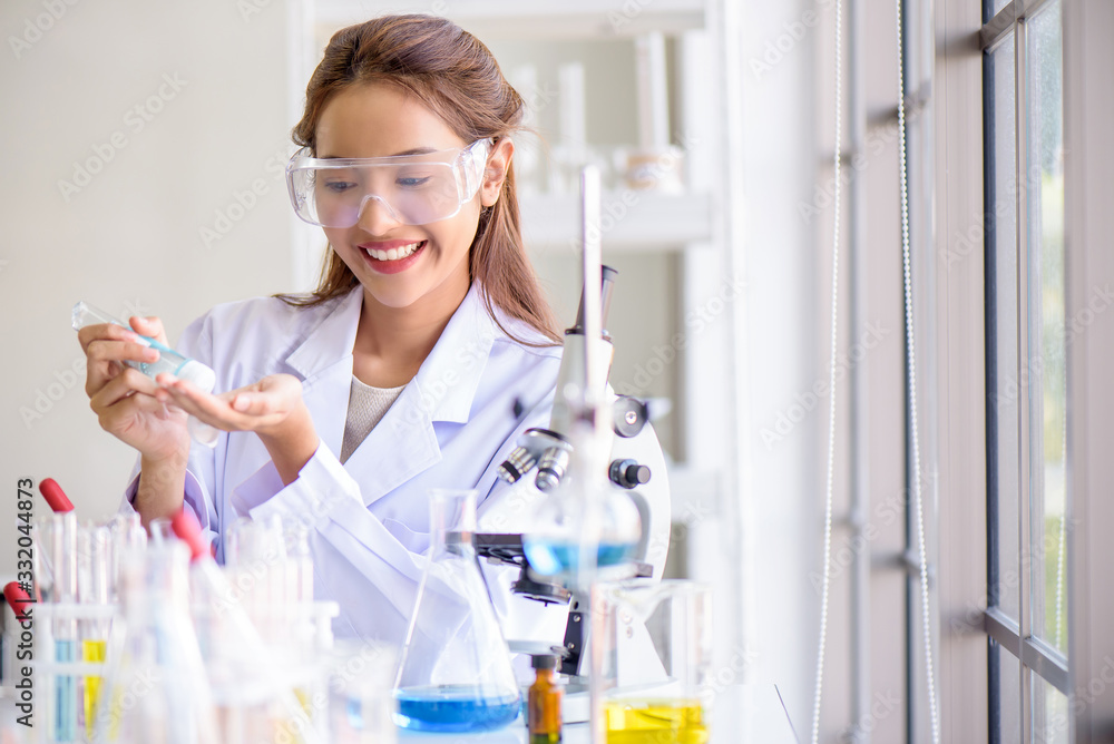Attractive happiness scientist woman lab technician assistant using alcohol hand gel to cleaning her hands at laboratory. Medical, pharmaceutical and scientific research and development concept. Attractive happiness scientist woman lab technician assistant using alcohol hand gel to cleaning her hands at laboratory. Medical, pharmaceutical and scientific research and development concept.