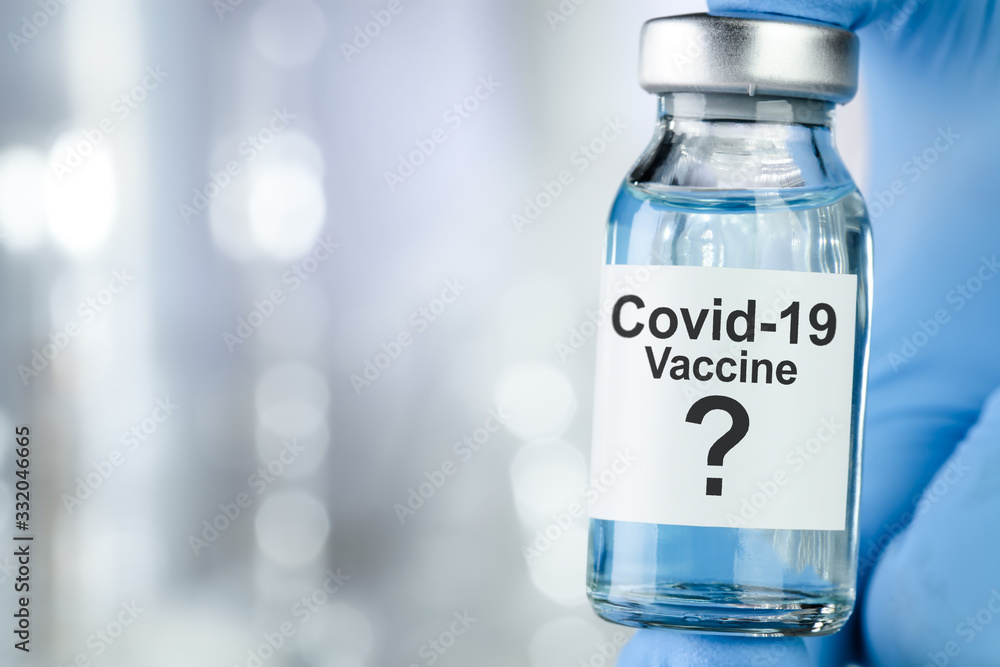 Possible cure concept with a hand in blue medical gloves holding Coronavirus, Covid 19 virus, vaccine vial Possible cure concept with a hand in blue medical gloves holding Coronavirus, Covid 19 virus, vaccine vial