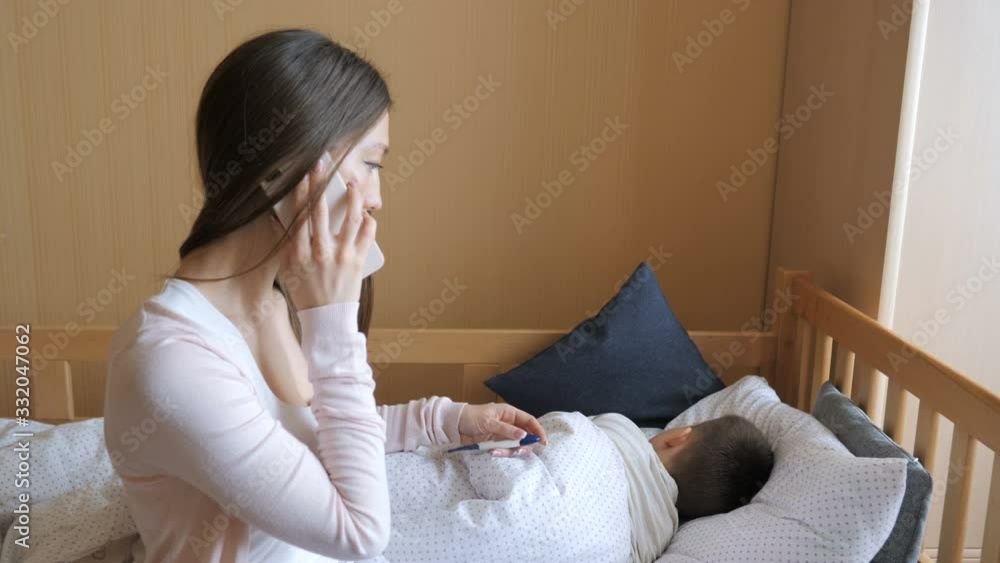 Mother measuring temperature of her ill kid and calling a doctor Mother measuring temperature of her ill kid and calling a doctor