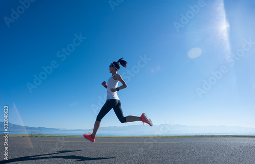Young fitness woman runner running on sunrise seaside trail