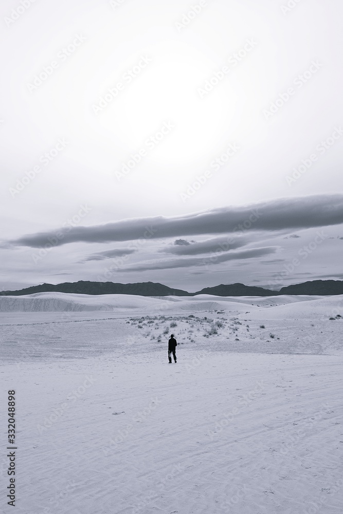 Black and white photo of person walking along Gypsum Dunes in White Sands