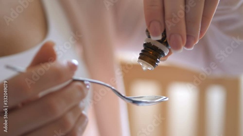 Sick child concept. Mother drops medicine on a spoon