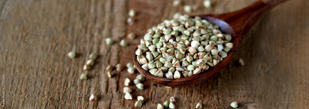 green buckwheat in a wooden spoon on a wooden background. rustic style organic. super food. healthy groats green buckwheat in a wooden spoon on a wooden background. rustic style organic. super food. healthy groats