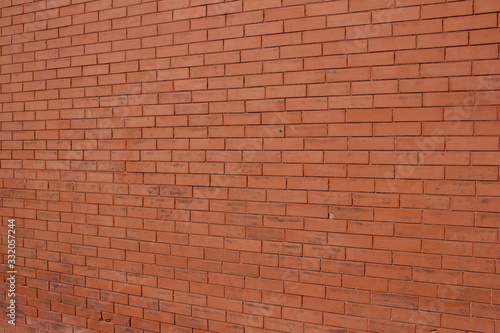 Vintage burnt orange color brick wall background with grungy texture (angle view)