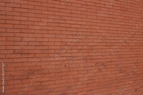 Vintage burnt orange color brick wall background with grungy texture (angle view)