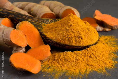 Turmeric powder and fresh turmeric (curcumin) on black background,Used for cooking and as herbal medicin.
