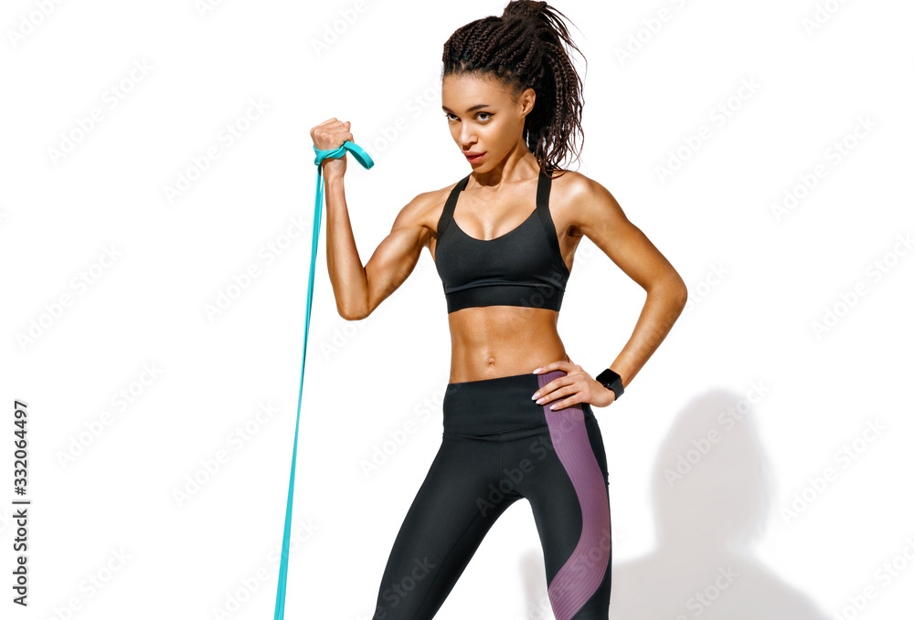 Strong girl using resistance band in her exercise routine. Photo of african american girl in black sportswear on white background. Strength and motivation Strong girl using resistance band in her exercise routine. Photo of african american girl in black sportswear on white background. Strength and motivation