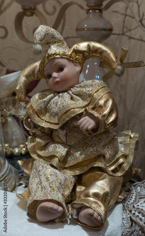 Toy harlequin child in a gold outfit playfully looks