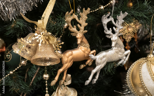 Fototapeta Naklejka Na Ścianę i Meble -  Christmas tree toys. Two deer of different colors and bells. Amid foliage