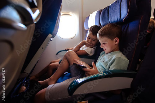 Leisure on the plane two boys play a tablet on a long flight.
