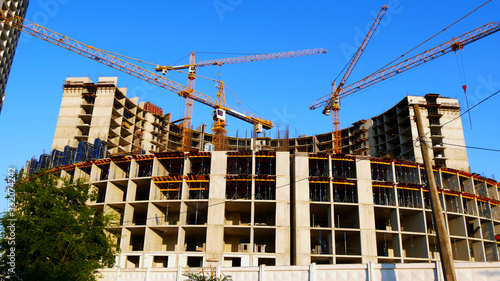 Four tower cranes erect an office building. A commercial building under construction. Construction site.
