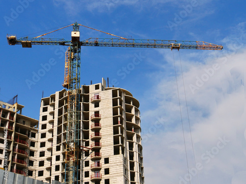 Building and crane under construction against blue sky.