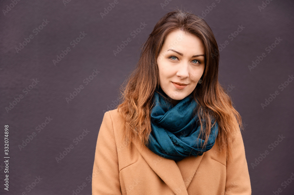 Portrait of a brunette girl in a autumn city in a coat walk a street on a background of a building wall Portrait of a brunette girl in a autumn city in a coat walk a street on a background of a building wall
