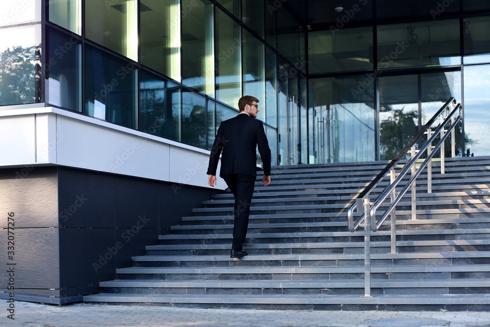 Stylish successful businessman goes up the stairs of the office building. Stylish successful businessman goes up the stairs of the office building.