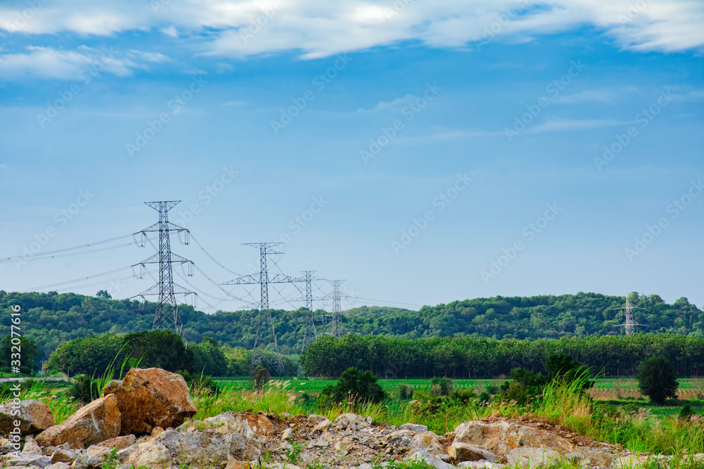 Obraz premium Electricity pole against sunset sky, Transmission line of electricity to rural with green tree, High voltage electricity pole with nature background, electricity transmission pylon