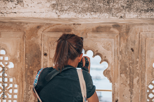 Canvas Print Woman tourist photographer takes photos while visiting the City Palace in Udaipu