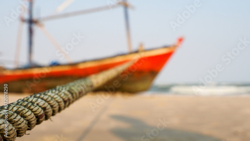 Closeup of a rope connected to an abandon wooden boat. Selected focus.