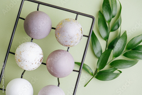 TOp view of gilded easter eggs and regular ones on metal egg holder and branches photo