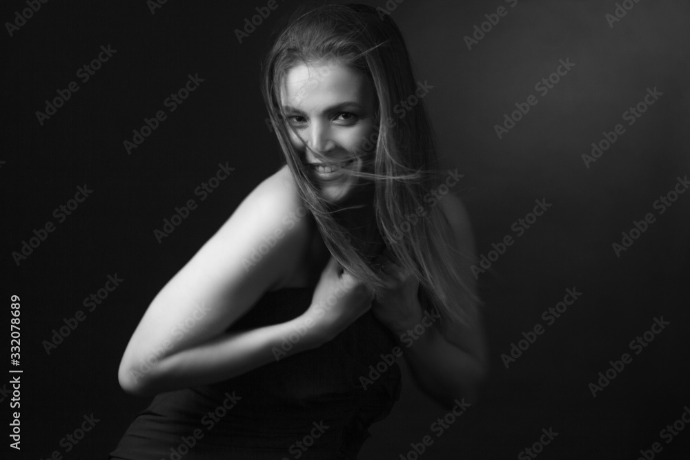 Classic black-and-white dramatic portrait of an adult blonde woman in Studio on black background.