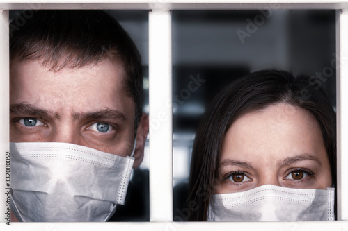 Quarantine. A sick man and woman in protective medical masks look through the hospital bars. emotions on the face - fear, fright and panic. the spread of epidemics and pandemics photo