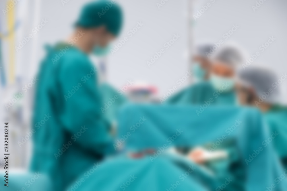Blurred image background of medical team performing surgical operation in operating room. An operating room may be designed and equipped to provide care to patients. Blurred image background of medical team performing surgical operation in operating room. An operating room may be designed and equipped to provide care to patients.