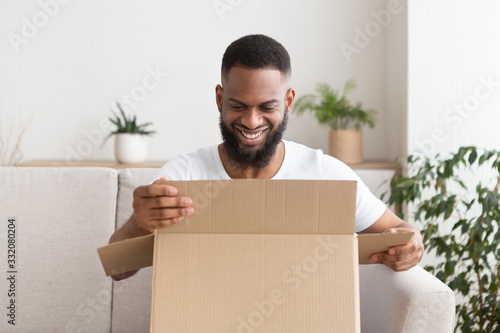 Tablou pe pânză Online shopping at home. Smiling guy unpack delivery