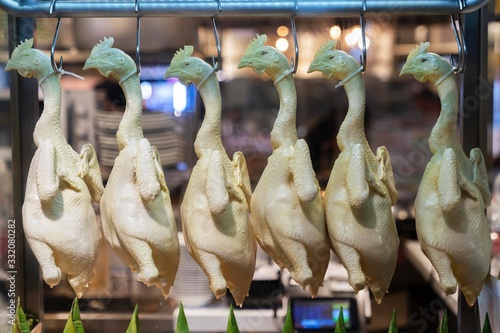 Valokuva group of raw chicken in a store, beautifully and neatly hung in one row in the refrigerator window