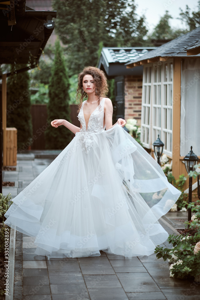 Fototapeta premium Young bride wearing wedding dress and posing outside