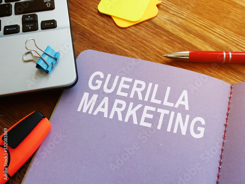 Fotografija Guerilla marketing guide and laptop on the desk.