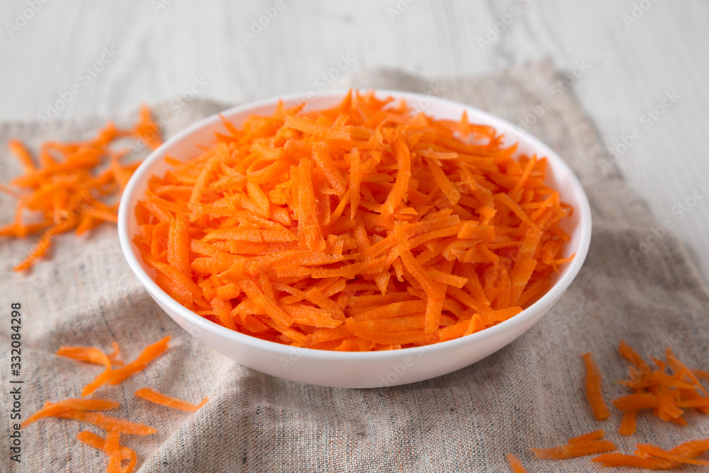 Shredded carrots in a white bowl, low angle view. Close-up. Shredded carrots in a white bowl, low angle view. Close-up.