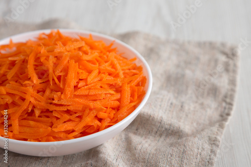 Shredded carrots in a white bowl, low angle view. Copy space.
