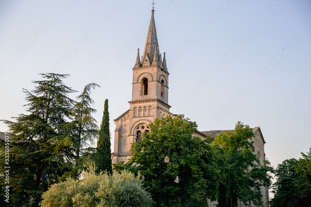 Church tower in a small Provencal town among the trees in the sunset light