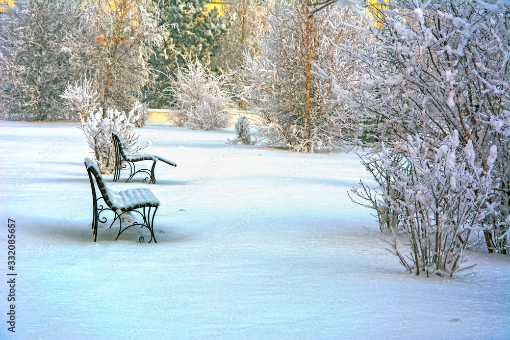 Snow covered bench in a deserted park. Winter. Russia	