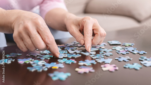 Senior woman playing jigsaw puzzle at home, empty space