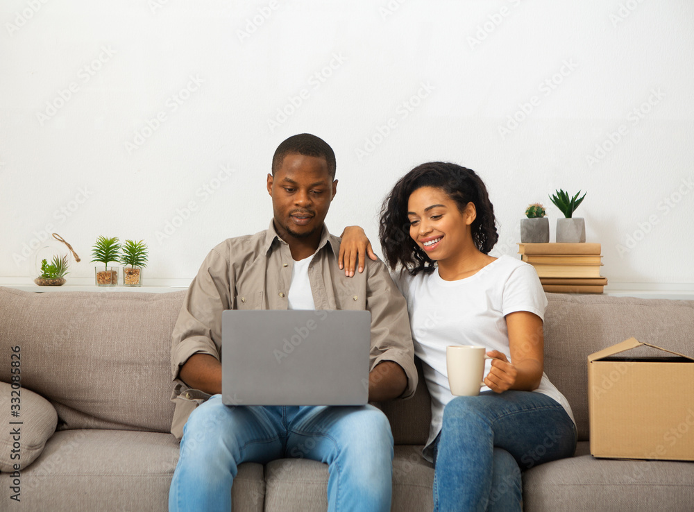 Man and woman looking at laptop and sitting on sofa Man and woman looking at laptop and sitting on sofa